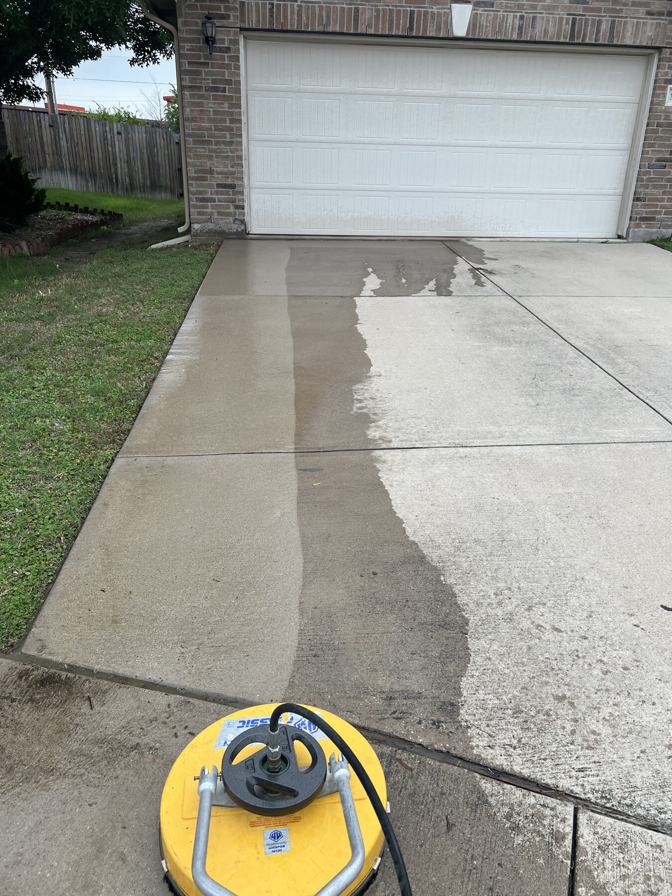 Surface cleaner on a residential driveway, clean path against soiled concrete
